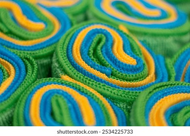 Colorful rolled towels in vibrant green, blue, and yellow patterns arranged neatly for display in a spa setting - Powered by Shutterstock