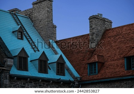 Colorful rooftops with dormer windows and stonework chimneys of residential buildings against a blue sky in historic Old Quebec in Quebec City, Canada