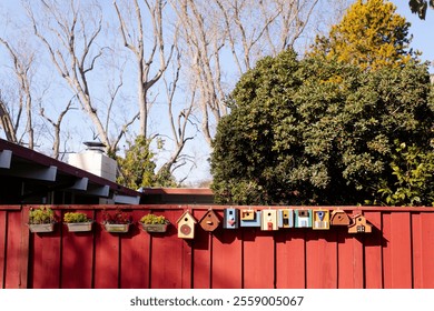 A colorful row of birdhouses attached to a fence, unique designs and color An artistic display of colorful bird houses, green trees in the background - Powered by Shutterstock