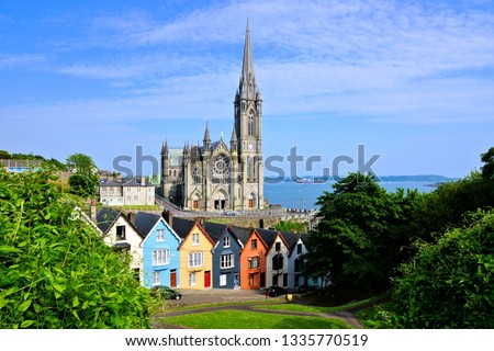 Colorful row houses with towering cathedral in background in the port town of Cobh, County Cork, Ireland