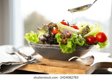 Colorful salad with fresh ingredients prepared with a spoon of olive oil in a ceramic bowl. Healthy nutrion concept for fitness and spring diet. 