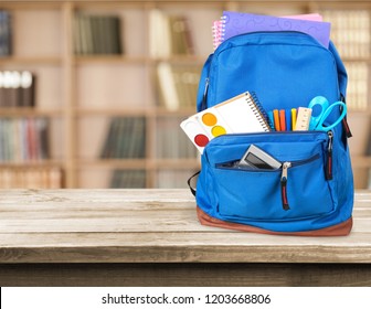 Colorful school supplies in backpack on wooden background - Shutterstock ID 1203668806