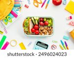 Colorful School Supplies and Healthy Lunchbox. Top view of vibrant school supplies arranged around a nutritious lunchbox with sandwich, fruits, and nuts. Back-to-school, education, nutrition concept.