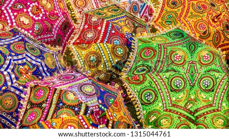 A colorful set of parasols with vibrant colors and intricate patterns, for sale as tourist souvenirs on a street in Jaipur, India.
