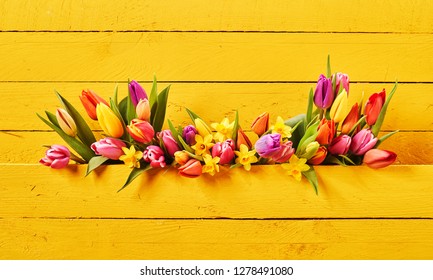 Colorful setting of fresh springtime flowers on yellow background of painted boards with copy space