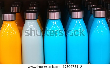 Colorful, shiny water bottles with metal caps. Carrying a water bottle helps keep you hydrated and healthy. Reusable containers cut down on waste.                              