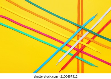 Colorful shoe laces on yellow background, closeup