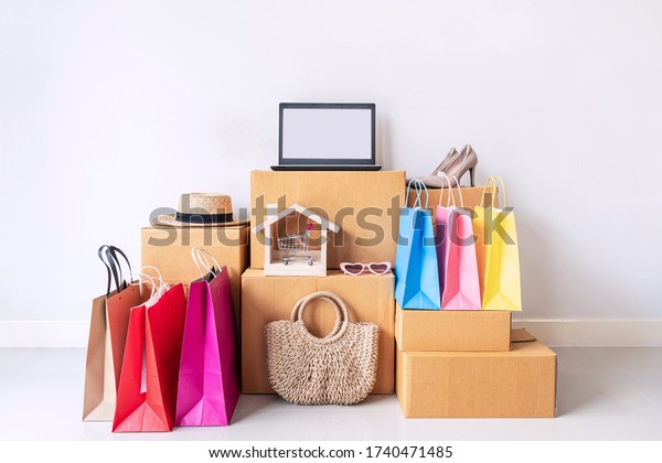 Colorful shopping bag with stack of cardboard boxes\
and fashion items at home, Website online shopping concept with\
copy space