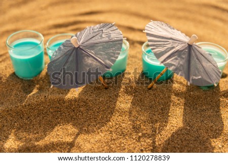 colorful shots drinks on a sandy beach with umbrellas for drinks, summer relax