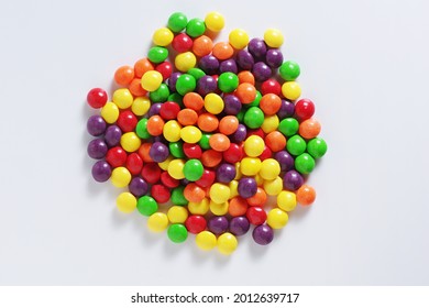 Colorful skittles candies on a white background, top view