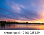 Colorful sky at sunset, light clouds, lake, forest