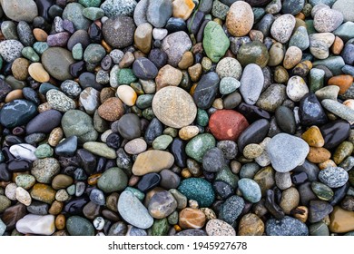 Colorful smooth rocks on the beach covered in water. - Powered by Shutterstock