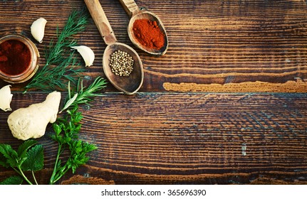 Colorful spices and green herbs on rustic wooden table