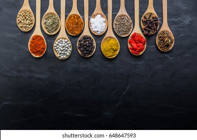 Colorful Spices In Wooden Spoon On Black Stone Back Ground With Copy Space For Back Ground.