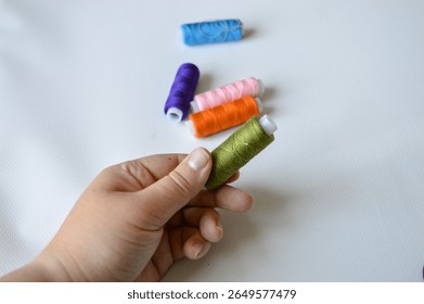 colorful spools of thread lined up on a white surface  great for themes like sewing, textile arts, tailoring, crafting, handmade, DIY projects, fashion design, or color coordination