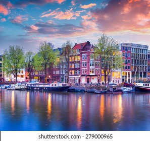 Colorful spring sunset on the canals of Amsterdam. Authentic Dutch architecture in the capital and most populous city of the Netherlands.