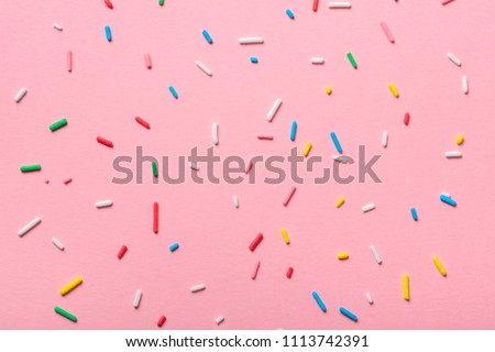 colorful sprinkles over pink background, decoration for cake and bakery 