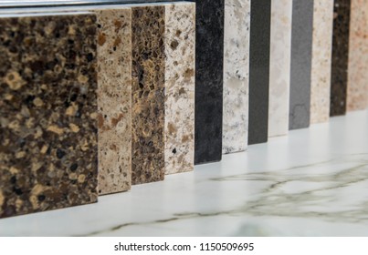 Colorful square color samples of kitchen granite, marble and quartz countertop, made of natural stone in line on white carrara marble slab with gray/brown grains