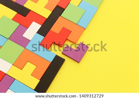 A colorful square tangram puzzle, over wooden table