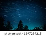 Colorful startrails above dark grim forest