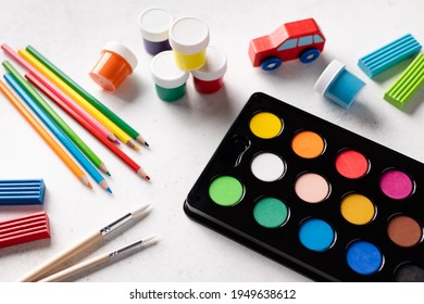 Colorful Stationery Set On White Background. Watercolor Paints In Box, Color Pencils, Gouache Cans, Clay. Back To School. Close-up