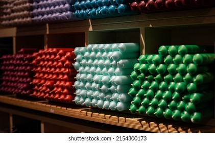 Colorful stick candles arranged on shelves and sorted by color in a candle shop.
