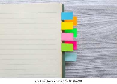 Colorful sticky notes among stack of books. Colorful sticky note bookmarks are attached to the notebook. Bookmarks in book on wooden table