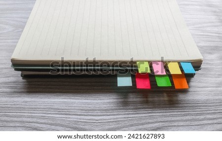 Colorful sticky notes among stack of books. Colorful sticky note bookmarks are attached to the notebook. Bookmarks in book on wooden table