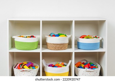 Colorful storage baskets on shelves. White shelving with rainbow wooden toys in cloth stylish baskets. Organizing and storage ideas in nursery. Interior design.  - Shutterstock ID 2220920747
