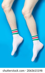 Colorful striped white socks feet, hairy legs studio photogrpahy blue
