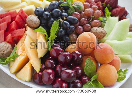 Colorful summer fruit platter with pineapple, watermelon, cherries, apricots, strawberries, cantaloupe, walnuts and mint