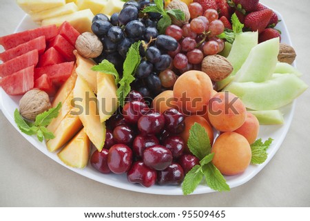 Colorful summer fruit platter with pineapple, watermelon, cherries, apricots, strawberries, cantaloupe, walnuts and mint