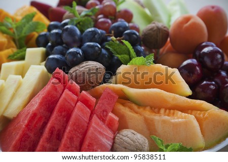 Colorful summer fruit platter with watermelon, cantaloupe, grapes, cherries, apricots, walnuts and mint