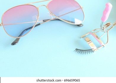 colorful sunglasses and eyelashes with lash comb of beauty product in pastel tone color on blue background. Cheerful background 