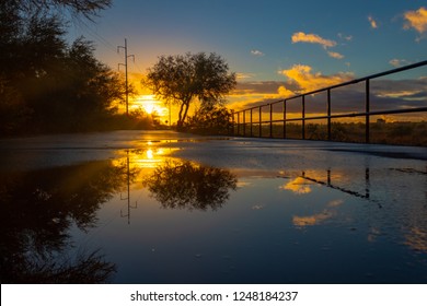 A Colorful Sunrise On The Loop, A Biking, Walking, Jogging And Running Path Or Trail That Circles The City Of Tucson, Arizona. Rain Puddles Offer Mirror Like Reflections Of The Beautiful Sky. 2018.