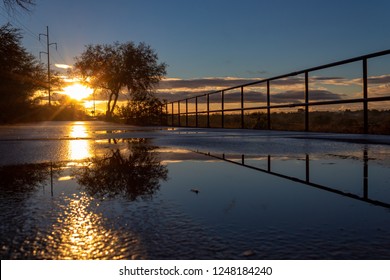 A Colorful Sunrise On The Loop, A Biking, Walking, Jogging And Running Path Or Trail That Circles The City Of Tucson, Arizona. Rain Puddles Offer Mirror Like Reflections Of The Beautiful Sky. 2018.