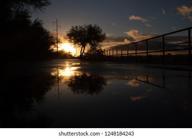 A Colorful Sunrise On The Loop, A Biking, Walking, Jogging And Running Path Or Trail That Circles The City Of Tucson, Arizona. Rain Puddles Offer Mirror Like Reflections Of The Beautiful Sky. 2018.