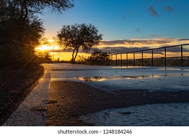 A Colorful Sunrise On The Loop, A Biking, Walking, Jogging And Running Path Or Trail That Circles The City Of Tucson, Arizona. Rain Puddles Offer Mirror Like Reflections Of The Beautiful Sky. 2018.