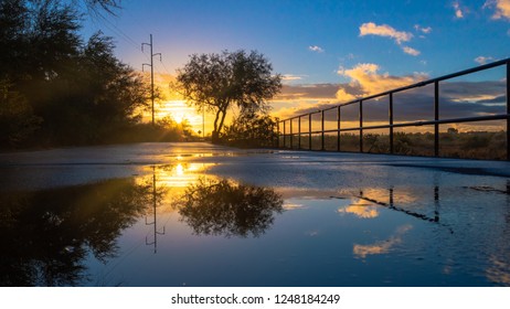 A Colorful Sunrise On The Loop, A Biking, Walking, Jogging And Running Path Or Trail That Circles The City Of Tucson, Arizona. Rain Puddles Offer Mirror Like Reflections Of The Beautiful Sky. 2018.