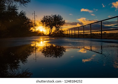 A Colorful Sunrise On The Loop, A Biking, Walking, Jogging And Running Path Or Trail That Circles The City Of Tucson, Arizona. Rain Puddles Offer Mirror Like Reflections Of The Beautiful Sky. 2018.