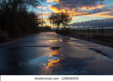 A Colorful Sunrise On The Loop, A Biking, Walking, Jogging And Running Path Or Trail That Circles The City Of Tucson, Arizona. Rain Puddles Offer Mirror Like Reflections Of The Beautiful Sky. 2018.