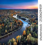 Colorful sunrise over the Gauja National park valley.  Sigulda city panorama from drone with forest in autumn colors.