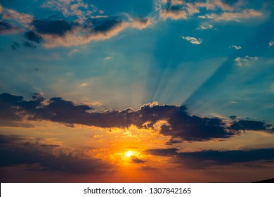 Colorful sunset in the blue sky.The rays of the sun breaking through the dark clouds. Abstract natural background. Beautiful nature
