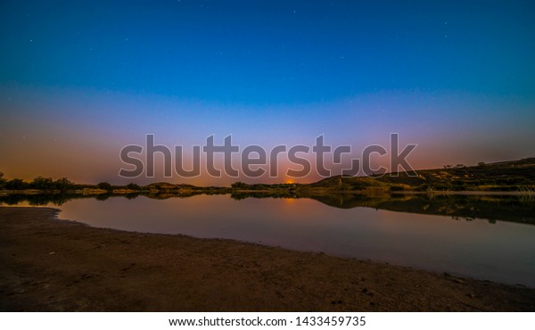 colorful sunset near a lake with\
reflections of the mountains on the water surface -\
Image