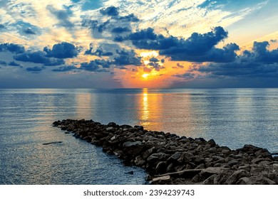 Colorful sunset on the Black Sea. Sea breakwaters. Seascape at sunset under a cloudy sky. Waves on the sea and dark clouds in the blue sky. Sunset over the sea with waves. - Powered by Shutterstock