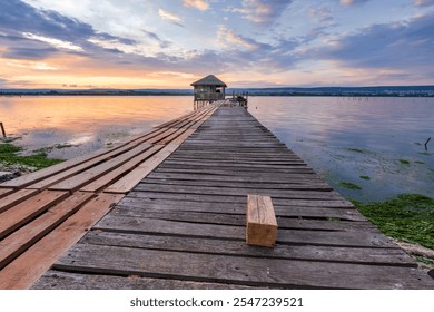 Colorful sunset on a lake with a wooden pier and small house in the end. - Powered by Shutterstock