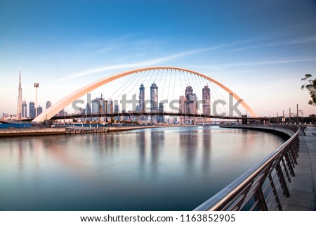 colorful sunset over Dubai Downtown skyscrapers and the newly built Tolerance bridge as viewed from the Dubai water canal.