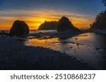 Colorful sunset at Ruby Beach featuring sea stacks silhouetted against the vibrant sky, with tide pools and driftwood on the pebble shoreline in Olympic National Park, Washington state, USA