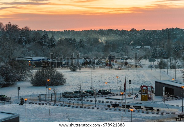 Colorful sunset in winter town whit frosty\
forest in background