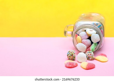 Colorful sweet different jelly candies in glass jar cup lying isolated on pink yellow background, pastry, confectionery, desserts. Tasty delicious unhealthy junk food. - Shutterstock ID 2169676233